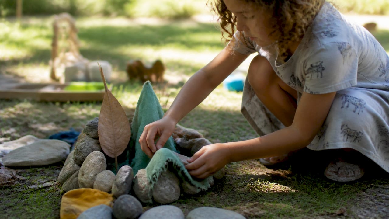 Child playing with natural loose parts outside