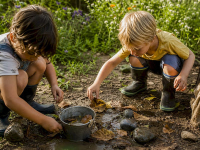 Children's hands playing with mud and sticks outside