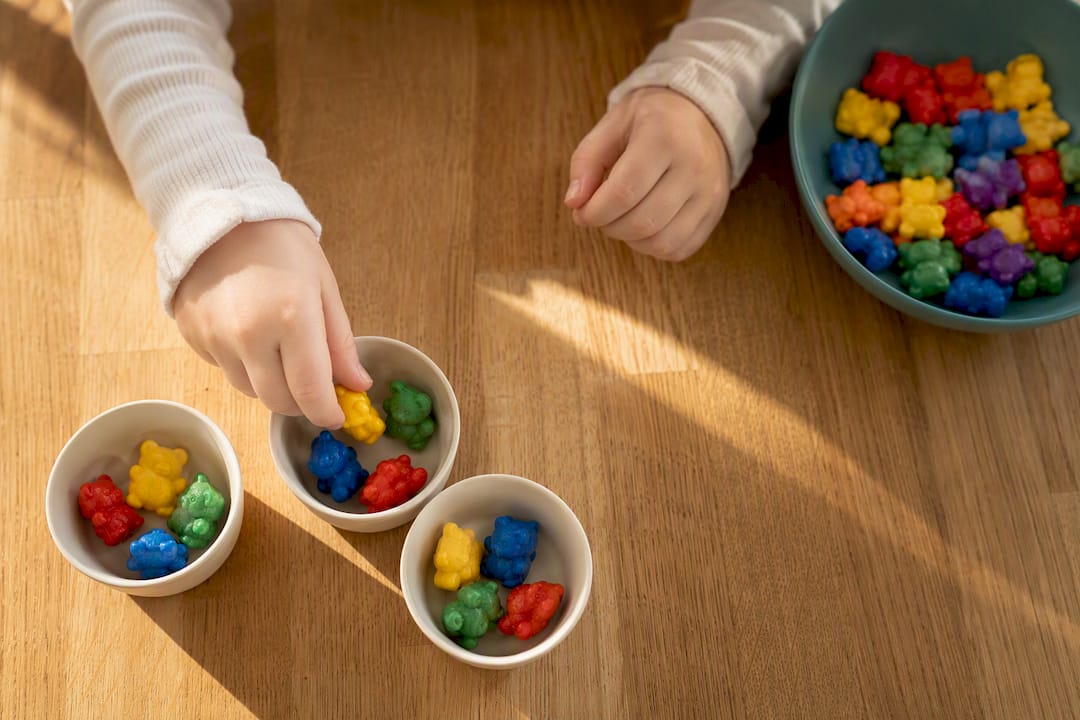 Hands arranging counting bears into equal groups