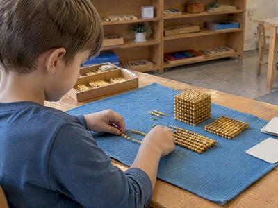 Child building numbers with Montessori golden beads