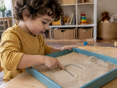 Preschool child tracing a letter in sand