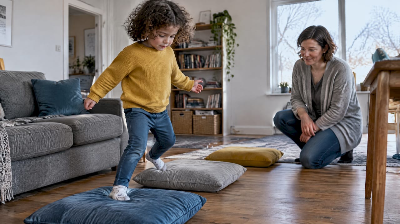 Child navigating a cushion course indoors