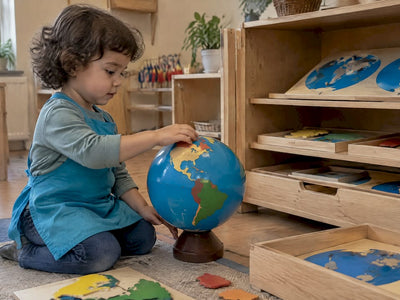 Preschooler exploring a globe beside geography materials