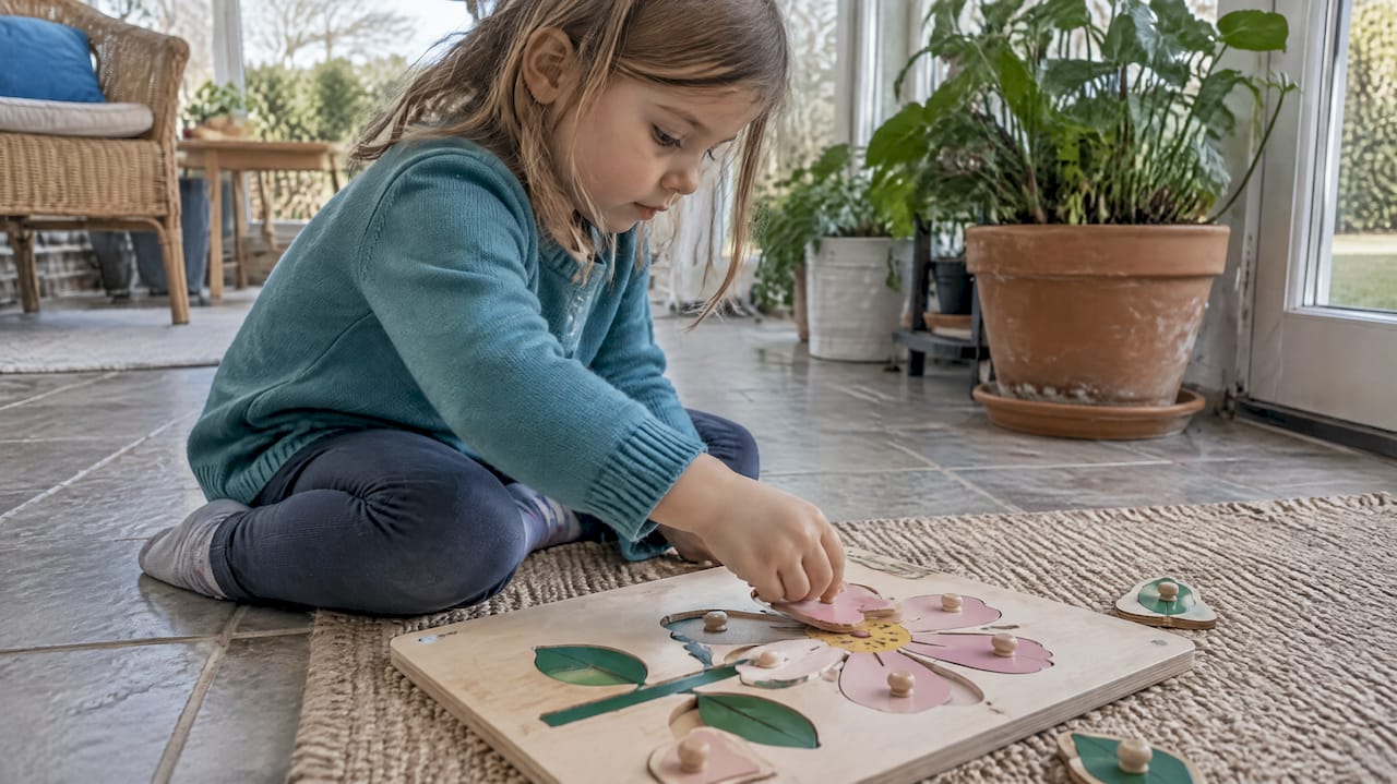 Child fitting a piece into a flower puzzle