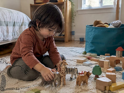 Child creating a story with blocks and wooden animals