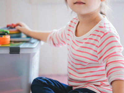 girl sitting on floor beside toys
