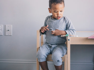 a little boy sitting on a chair playing with his toys