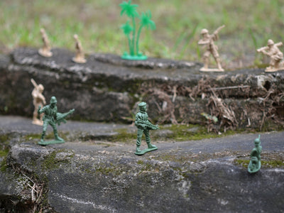 a group of toy army men standing on top of a rock