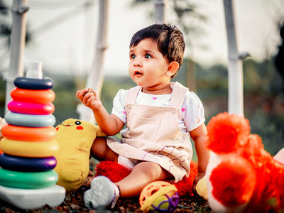 a little girl sitting on the ground next to a pile of toys