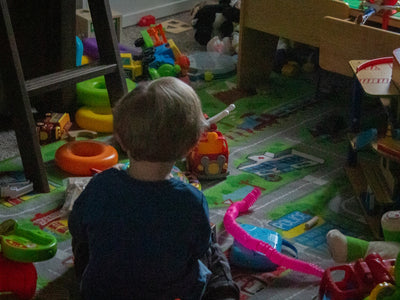 a little boy sitting on the floor in a room full of toys