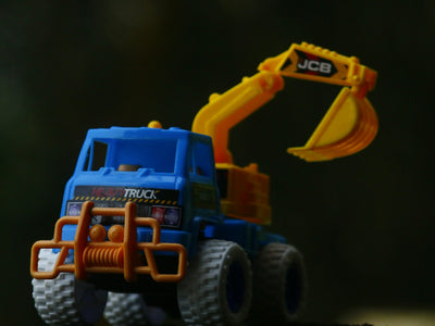 A blue toy truck with a yellow bulldozer on top of it