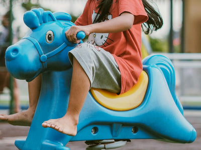 A happy girl rides a spring horse at the park.