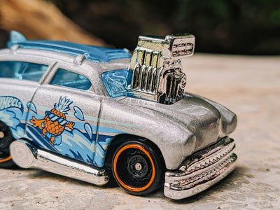 A hot wheels car is on a stone surface.