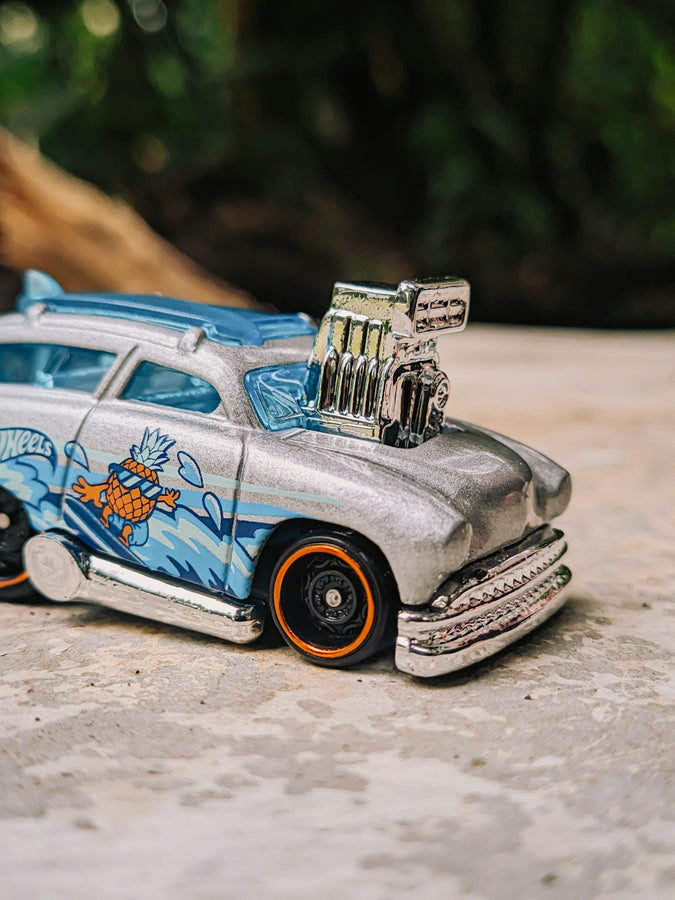 A hot wheels car is on a stone surface.