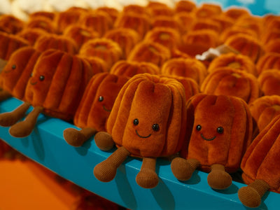 Row of cute, orange, pumpkin-shaped stuffed toys