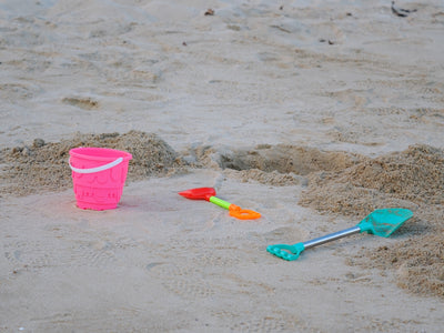 Pink bucket and beach toys on sand