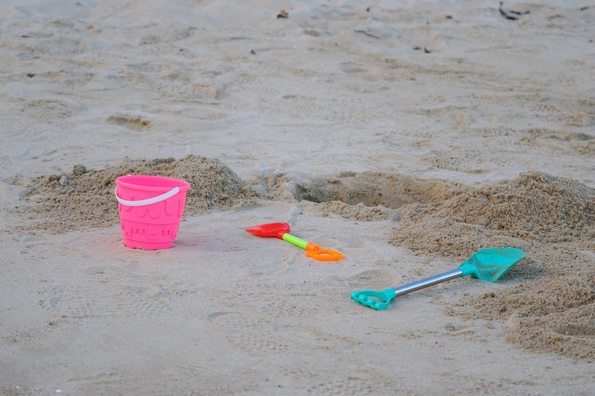 Pink bucket and beach toys on sand
