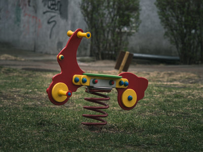 A red spring rider toy in a park.