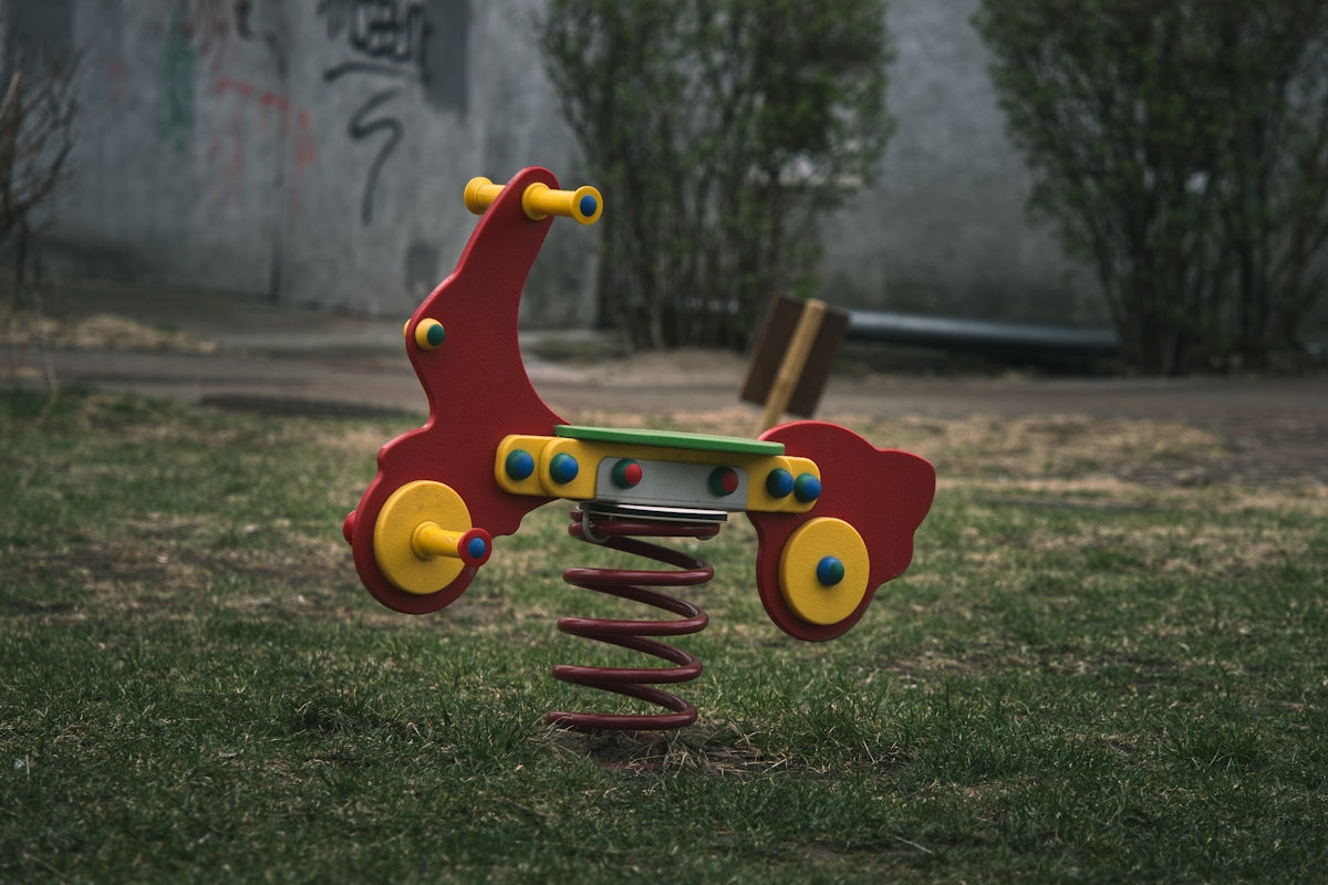 A red spring rider toy in a park.