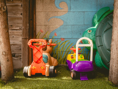 Two colorful ride-on toys in a grassy area.