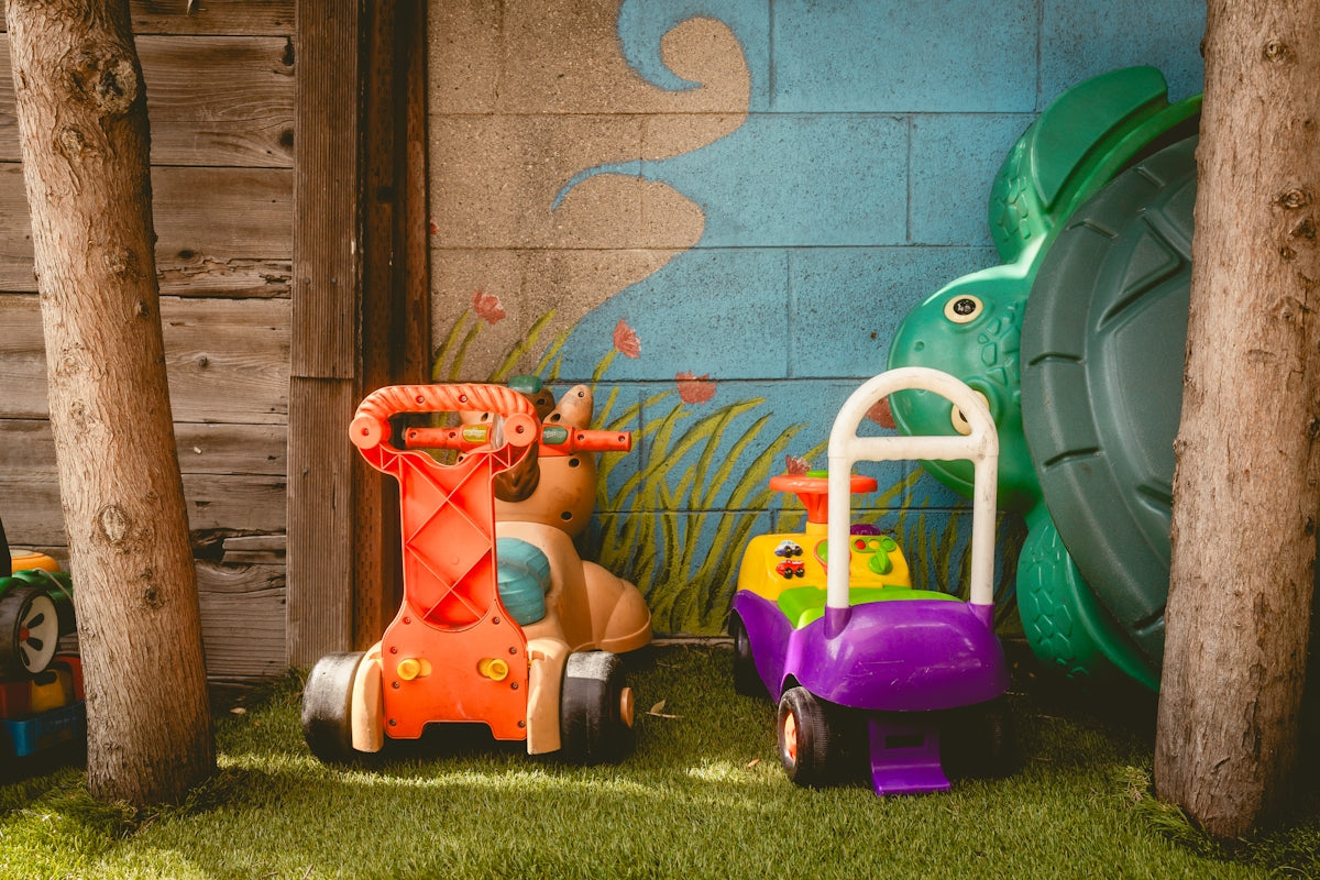 Two colorful ride-on toys in a grassy area.