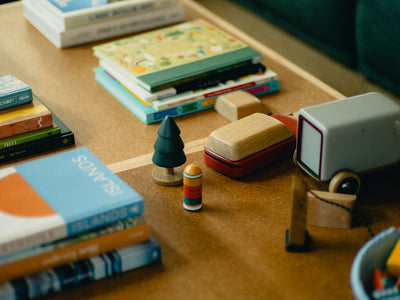 Stack of books and toys on a wooden table.