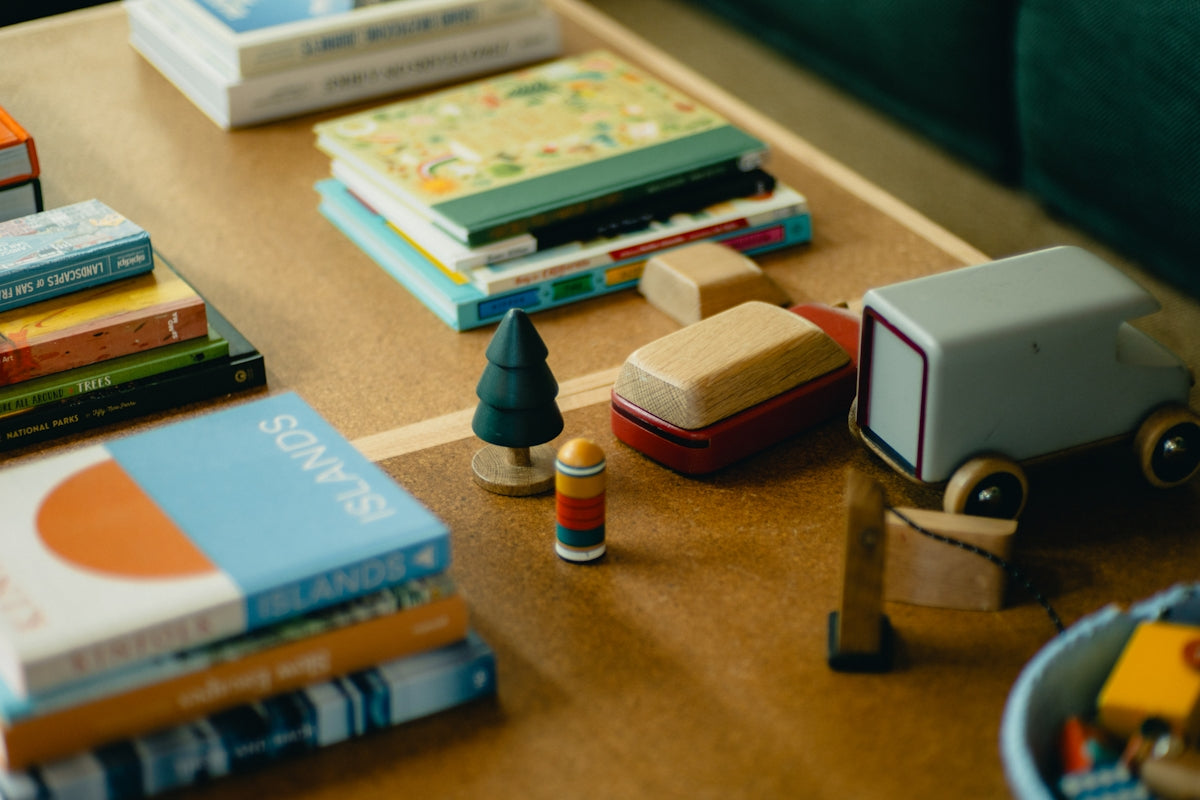 Stack of books and toys on a wooden table.