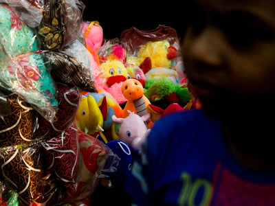 A child looks at colorful stuffed toys at a market