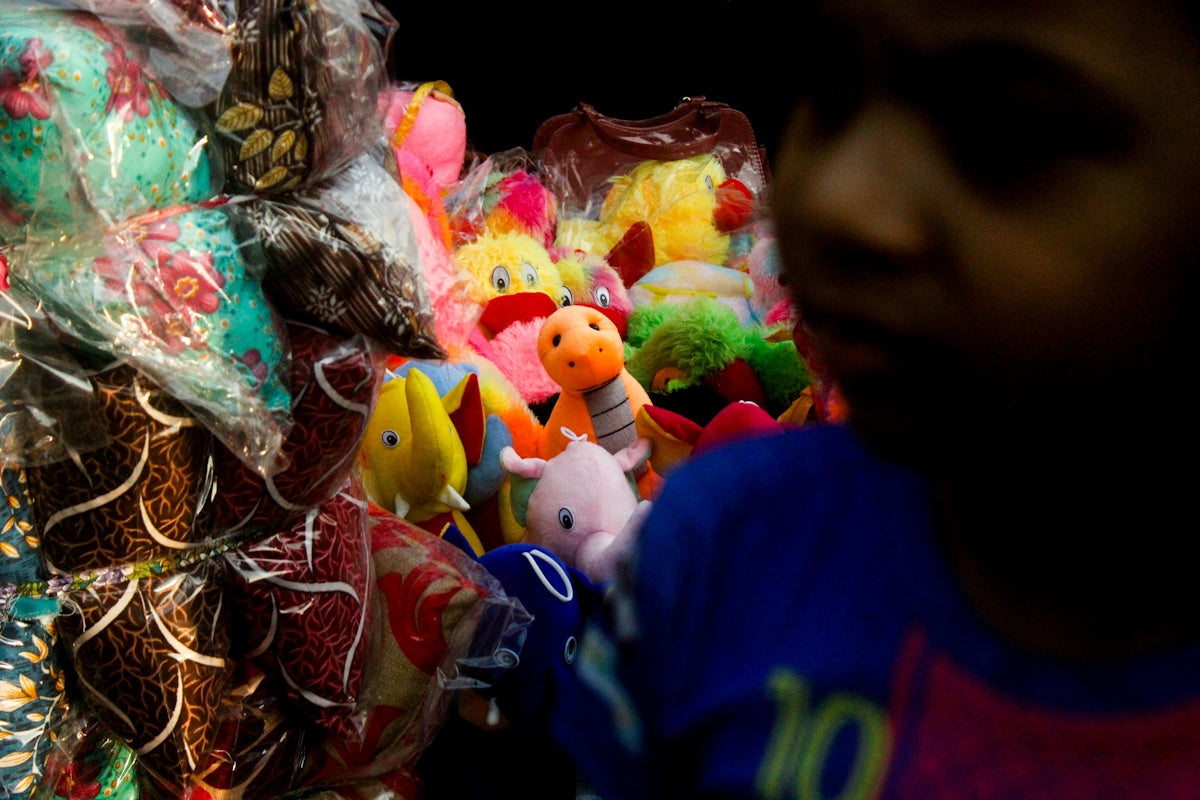 A child looks at colorful stuffed toys at a market