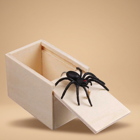 Prank spider jump-scare box on a beige studio background